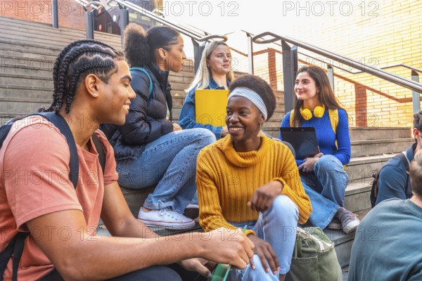 Diverse group of young students sitting on university campus steps, happy and smiling while discussing, representing education, friendship, and diversity in a college environment