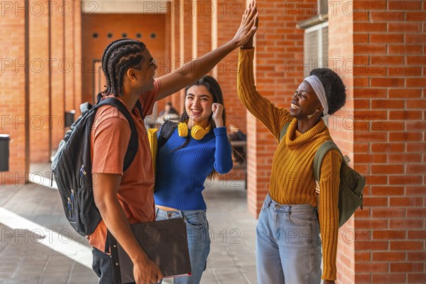 Diverse university students high fiving outdoors, celebrating teamwork and friendship on campus, smiling with backpacks and books, joyful about academic success and future goals