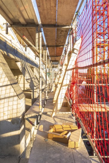 A scaffolding with wooden panels and casting shadows on a construction site, carpentry construction, roof extension, renovation, Stuttgart, Germany