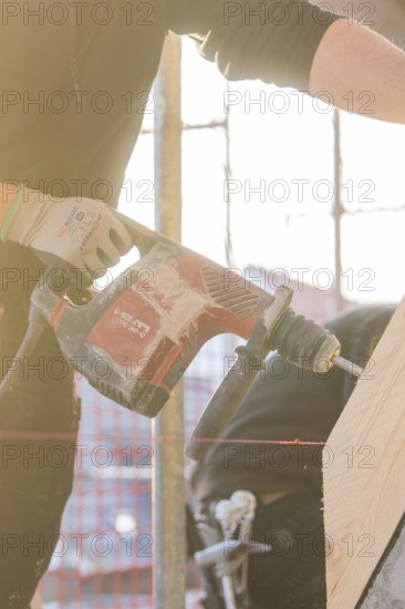 Close-up of workers with drill, wood and sunlight on construction site, carpentry construction, roof extension, renovation, Stuttgart, Germany