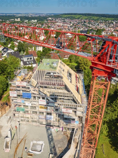 Crane rising high above a construction site with urban landscape in the background, construction site of a carpentry workshop, roof extension, renovation, Stuttgart, Germany