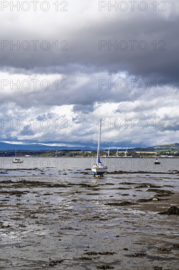 Boats on mud of Forth Estuary over Blackness Castle, Blackness, Scotland, UK