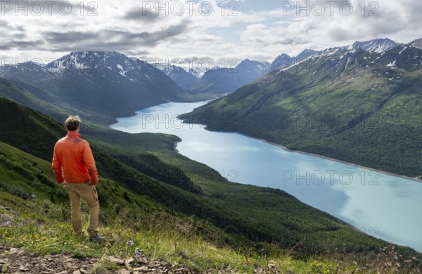Mountaineer enjoys views of blue lake and mountains on Twin Peaks Trail, Eklutna Lake, Chugach Mountains, Chugach State Park, Alaska, USA