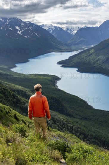 Mountaineer enjoys views of blue lake and mountains on Twin Peaks Trail, Eklutna Lake, Chugach Mountains, Chugach State Park, Alaska, USA