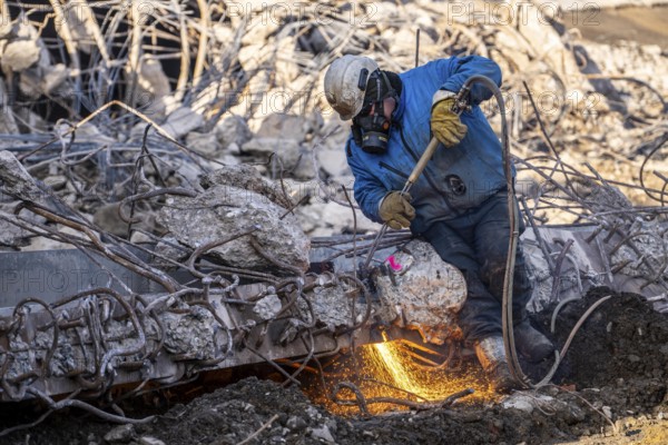 Workers with cutting torches demolishing the 120-meter long motorway bridge of the A516, across Teutoburger Straße in Oberhausen-Sterkrade, the bridge, built in 1970 was severely damaged, traffic continues to roll on the remaining west bridge, after demolition, the eastern part is rebuilt using a process that is unique in the world to date, 40 meter long precast concrete beams are assembled one after the other, reducing construction time from 24 to 7 months, After the completion of this bridge, the western part will also be rebuilt, North Rhine-Westphalia, germany