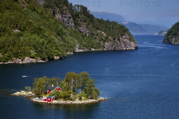 Small island with house in Lovrafjord, surrounded by blue water and green hills