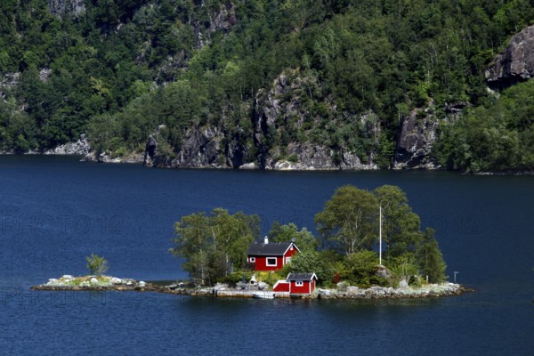 Small island in Lovrafjord with a red house surrounded by blue waters, Lovrafjord, Ryfylke, Norway