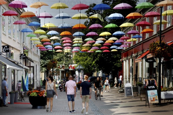 Colourful umbrellas decorate Dronningens gate, lively with passers-by, Trondheim, Norway