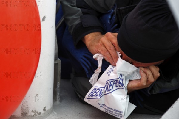 Person uses a vomit bag during a whale watching trip, Andenes, Vesterålen, Norway