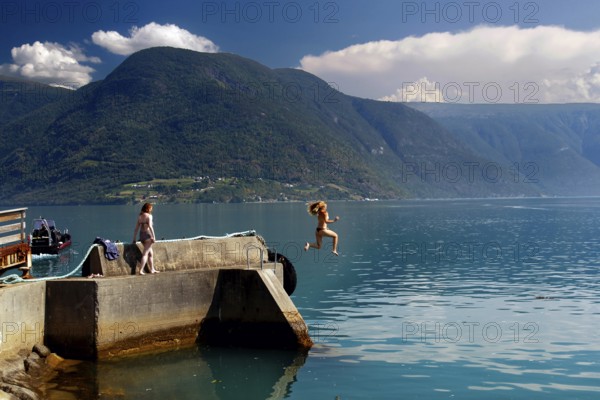 Summer jump into cool water from a jetty in the fjord, Solvorn, Norway