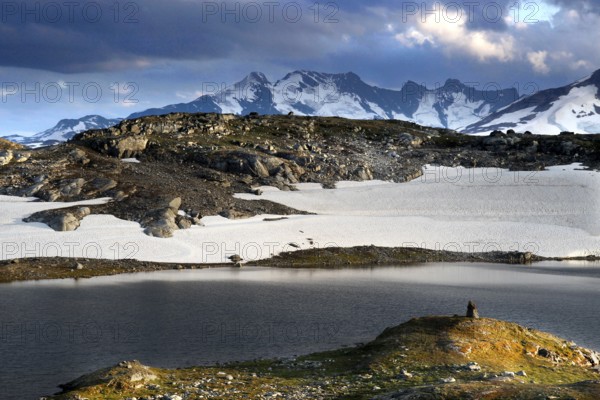 Snow-capped mountains and a calm lake under dramatic sky, mountains, Norway