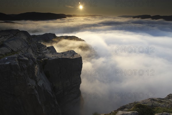Prekestolen in calm morning light at sunrise with clouds and fog