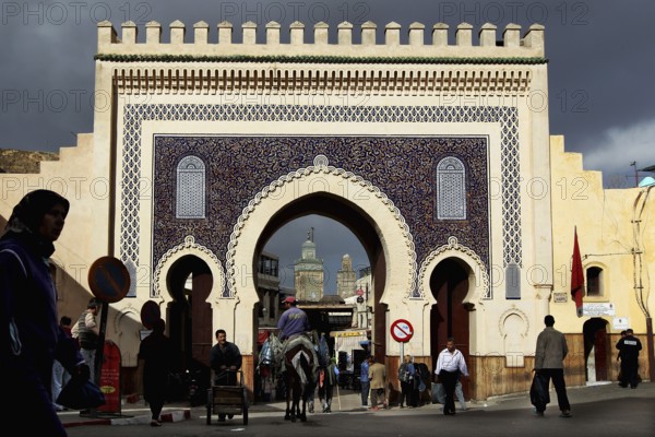 The decorative Bab Boujeloud city gate in Fez with pedestrians and distinctive architecture, Fez, Morocco