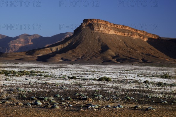Dramatic rock formations in dry desert landscape under blue sky, Gourrama, Morocco