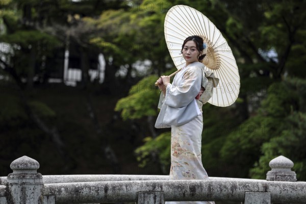 Woman wearing kimono with umbrella posing on a bridge in Manyama Park, Kyoto, Higashiyama, Japan