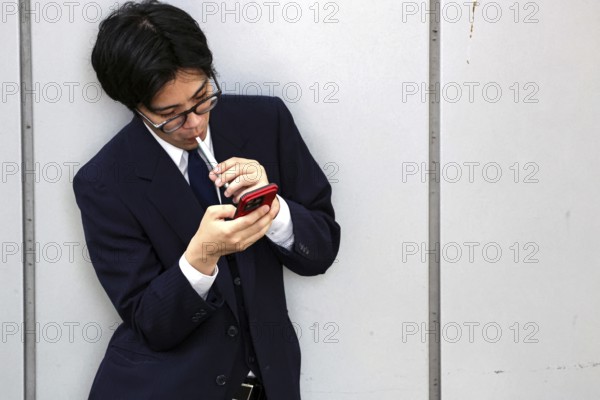 A businessman at Kyoto Central Station, immersed in his smartphone, Kyoto, Japan