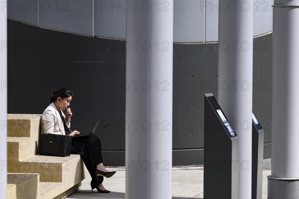 An office lady taking a break from work at Kyoto Central Station, Kyoto, Japan