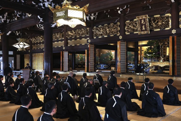 Interior view of Honganji Temple with monks meditating in traditional dress, Kyoto, Japan
