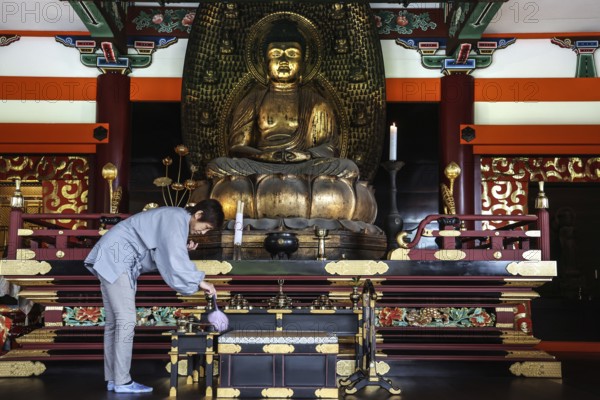 Woman cleaning a magnificent Buddha temple altar, Kyoto, Higashiyama, Japan