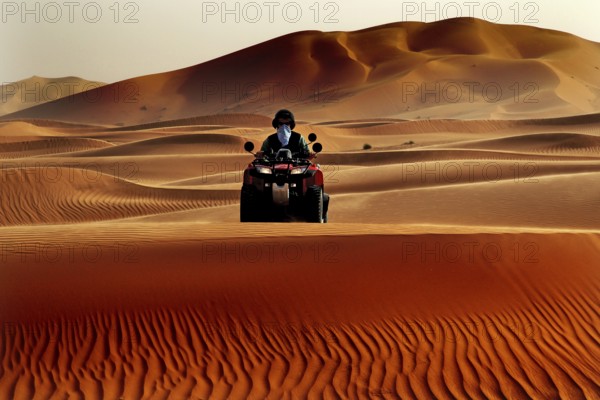 Person riding a quad bike through the vast sand dune landscape of Erg Chebbi, Erg Chebbi, Morocco
