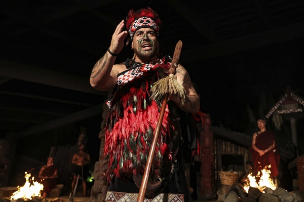 Maori chieftain in traditional dress at night with fire in the background in Rotorua, Rotorua, Bay of Plenty, New Zealand