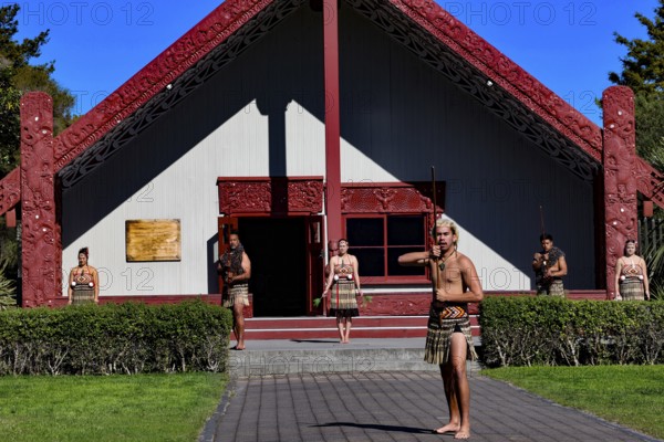 Maori group performs a welcoming ceremony in front of a traditional marae in Rotorua, Rotorua, Bay of Plenty, New Zealand