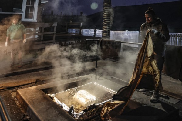 Preparation of a traditional hangi at night in Rotorua with a steaming pit, Rotorua, Bay of Plenty, New Zealand