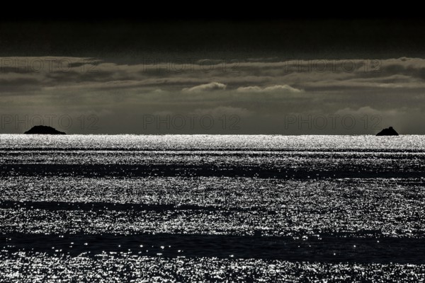 Waves reflect light and create an atmospheric image at dusk, Bay of Islands, New Zealand