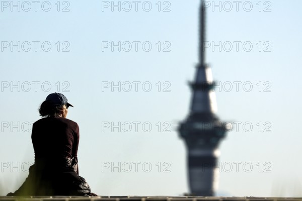 Person sitting in front of Sky Tower and enjoying the view in clear skies, Auckland, New Zealand