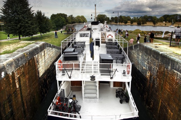 A ship passes the lock on the Göta Canal in Berg, surrounded by nature and clouds, Berg, Östergötland, Sweden