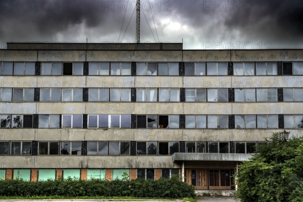 Dilapidated prefabricated building with empty windows under dramatic sky, Liepaja, Karosta, Latvia