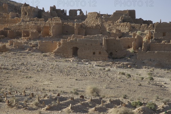 Dilapidated clay structures in a dry, barren landscape in Atchana