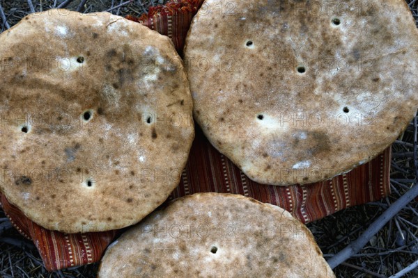 Three large flatbread loaves on a support in the desert, Beni Tajite, Morocco