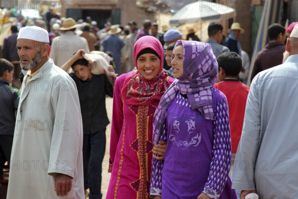 Smiling woman wearing lively traditional clothes at a busy market in Achaouikh, Achaouikh, Morocco