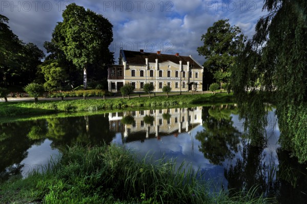 Kuldiga District Court with reflection in a quiet pond and surrounded by trees, Kuldiga, Courland, Latvia