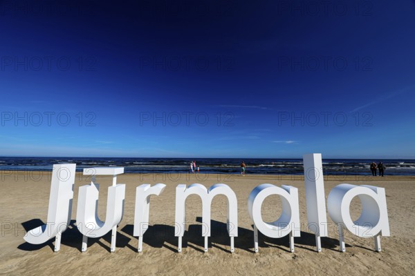 Large Jurmala logo on extensive beach under clear blue sky, Majori, Jurmala, Latvia