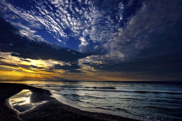 Sunset over sea with reflecting water under dramatic clouds, Kolka, Latvia