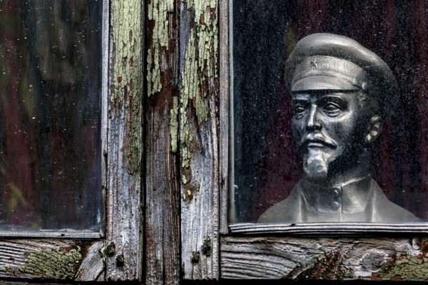 Lenin bust stands behind a dilapidated window in Kuldiga's old town, Kuldiga, Latvia