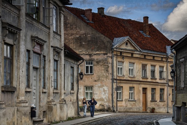 People walk through old town streets with old buildings in Kuldiga, Kuldiga, Latvia