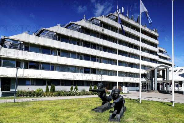 Modern sanatorium building with flags and well-kept green area against blue sky, Vaivari, Jurmala, Latvia