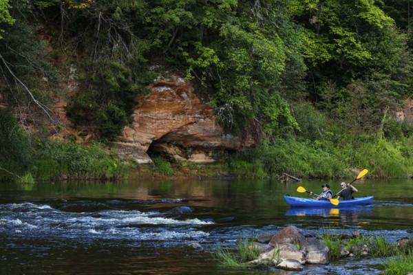 Two people in a canoe paddle through Gauja National Park along the imposing rocks, Gauja National Park, Latvia