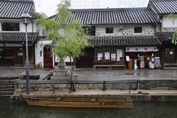 Traditional buildings along a canal in Kurashiki with a small boat in the foreground, Kurashiki, Okayama, Japan
