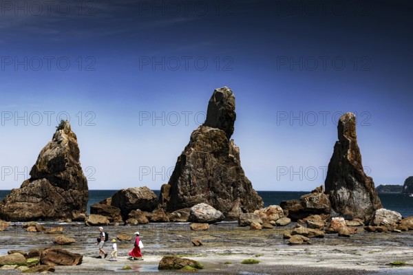 Large coastal rock formations under clear blue sky with walkers, Kushimoto, Japan