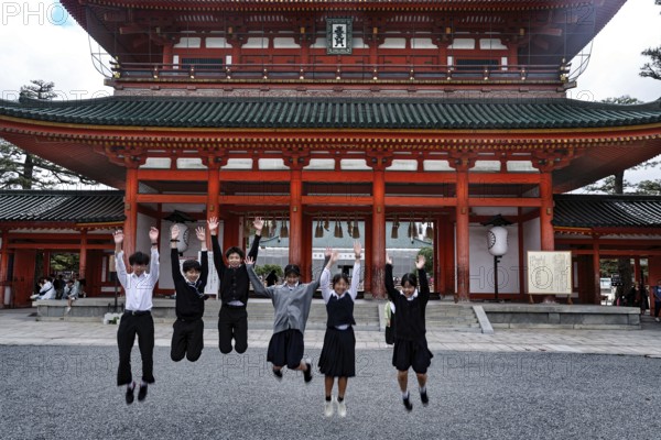 Group of students jump in front of a large torii in Kyoto, Kyoto, Okazaki, Japan