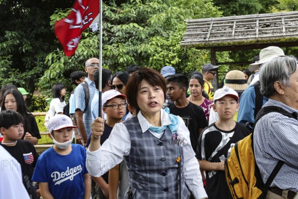 Tour guide leads tourist group at the Golden Temple, Kyoto, Japan