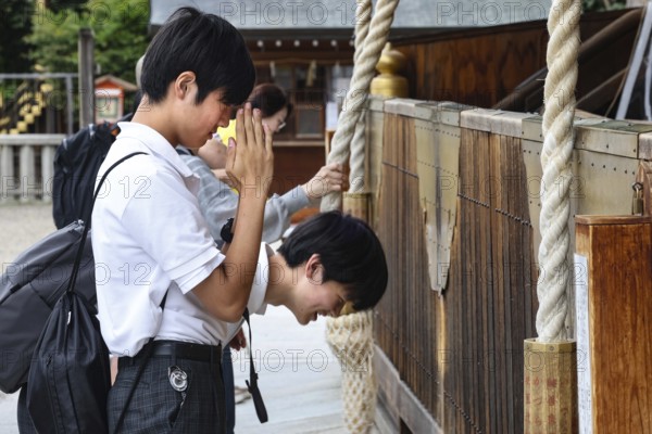 Students pray in front of a wooden shrine in Yasaka-jinja Temple, Kyoto, Higashiyama, Japan