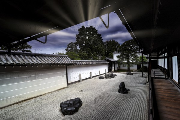 Zen garden with textured sand patterns and rocks surrounded by traditional Japanese architecture, Kyoto, Japan