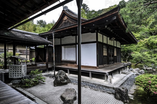 Zen garden with traditional pavilion surrounded by carefully arranged rocks and green vegetation, Kyoto, Japan