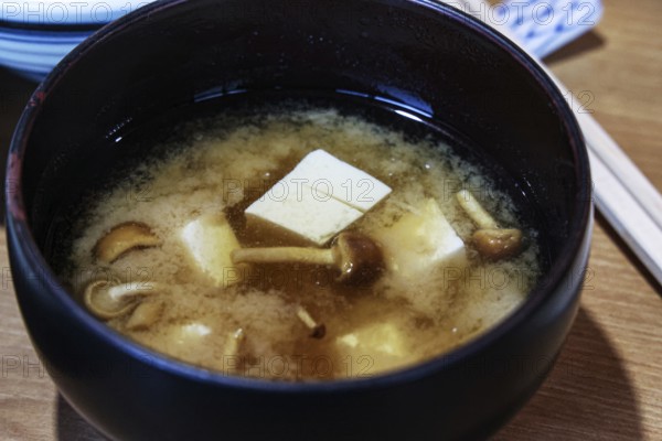 Spicy miso soup with tofu and mushrooms in a dark bowl, Matsumoto, Japan