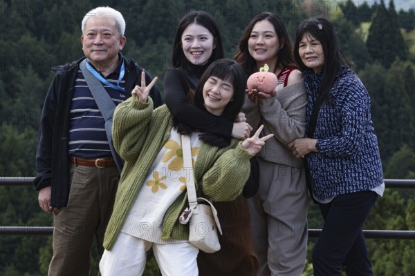 A group of tourists poses happily against a picturesque backdrop in Magome, Magome, Japan